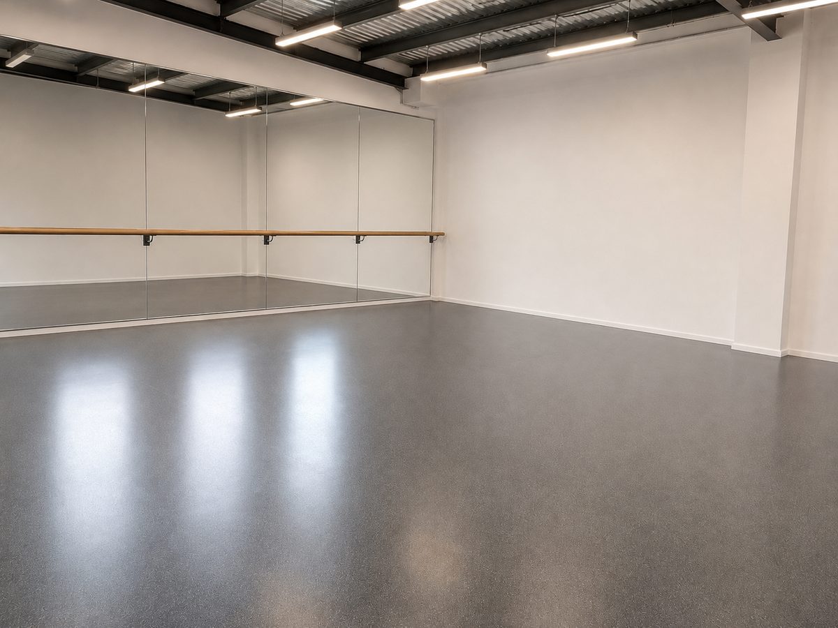 Dance studio with a sprung floor and dark acoustic vinyl overlay, wall mirror and ballet barre