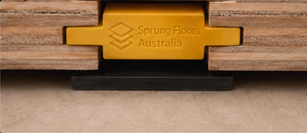The Sprung Floors Australia panel-and-clip sprung floor system, plywood panels joined by a branded clip over a resilient pad