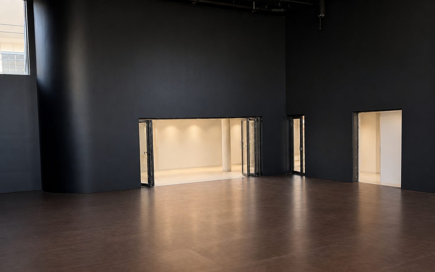 Performance theatre with a dark sprung floor and Weathertex overlay, opening to a lit foyer